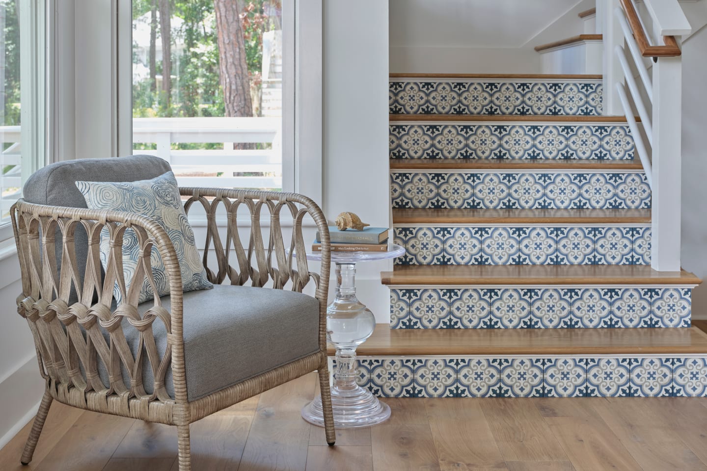 A hand-painted blue-and-white tile stair beside a woven chair in a Lowcountry home