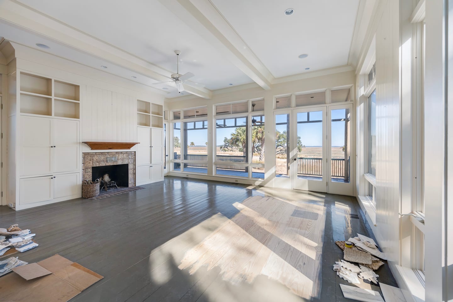 The original living room before renovation: brick fireplace and built-ins facing the porch and marsh