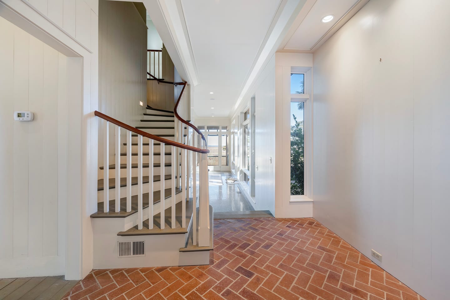 The curved staircase before renovation, rising from the herringbone brick hall