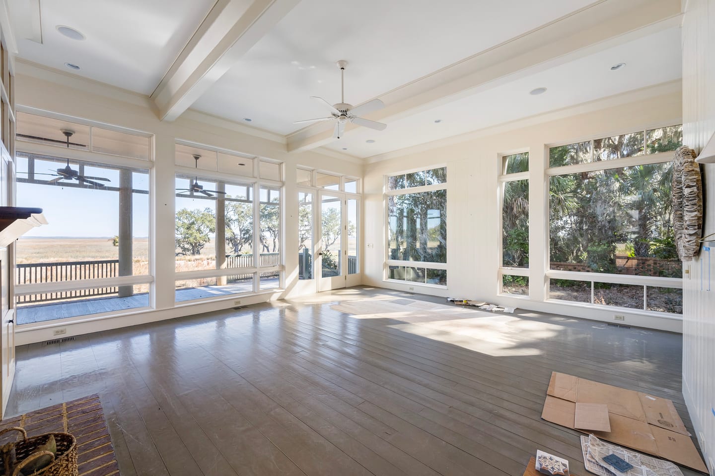 The marsh-front sunroom before renovation: a wall of windows over the deck and water