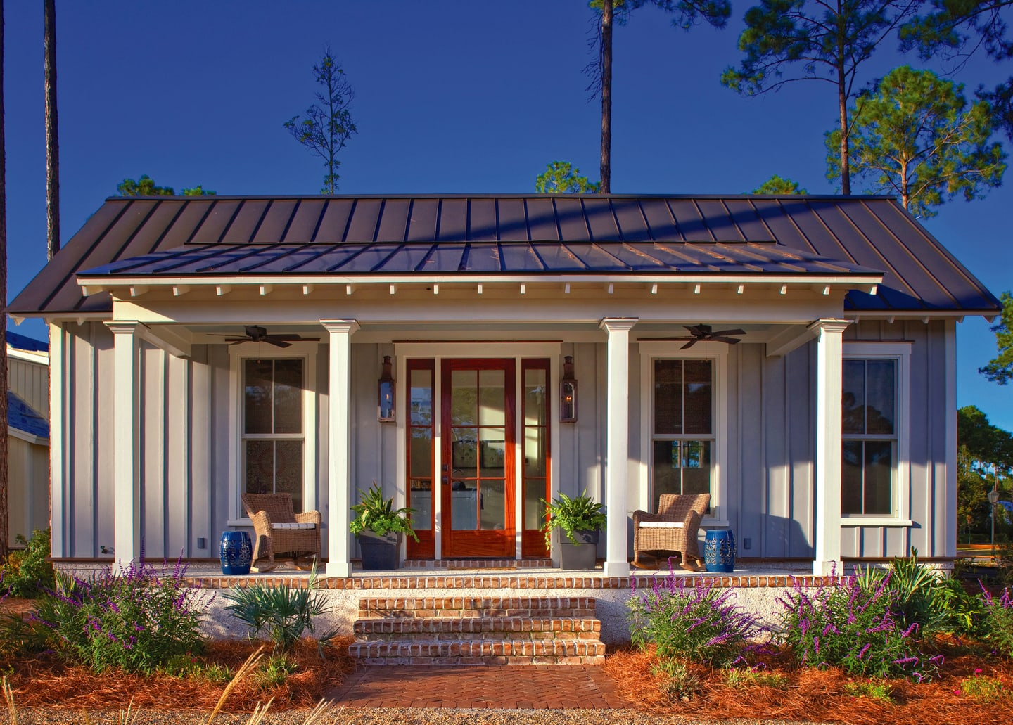 The Lowcountry bungalow at Duck Crossing, Palmetto Bluff: a deep front porch with rocking chairs, a red front door and purple salvia