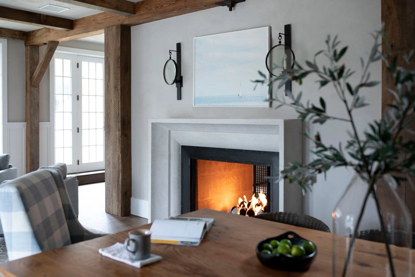 Dining room of the Main Line Historic Barn: hand-troweled plaster, a custom metal fireplace surround and stone mantel beneath the new timber frame