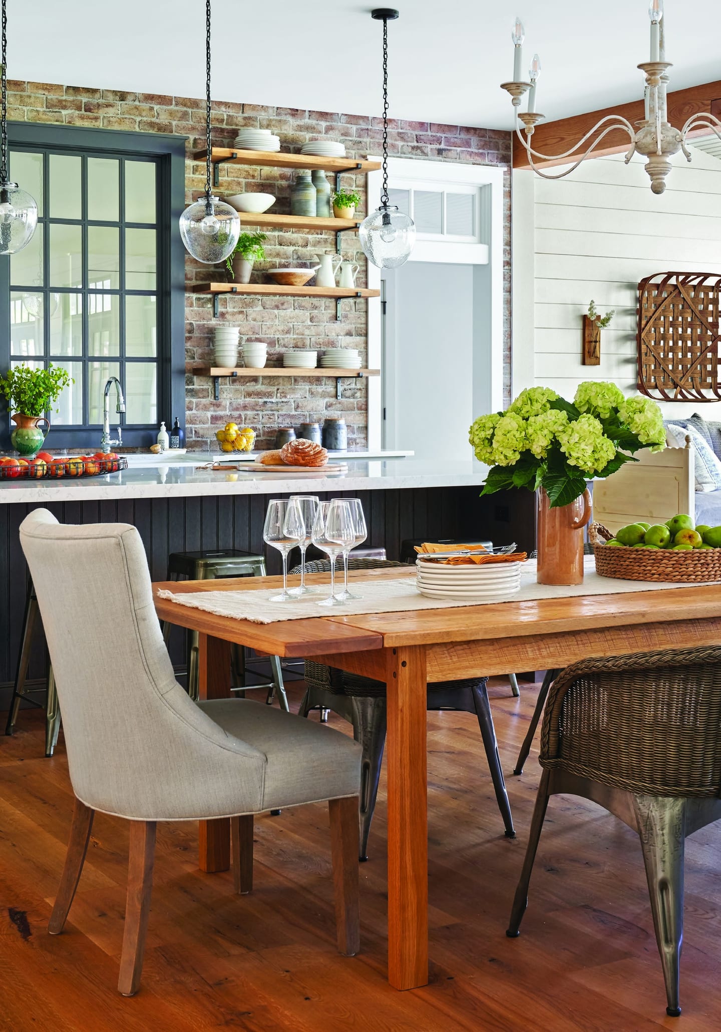 The Huckleberry dining room: a reclaimed-wood table, wicker chairs and a brick-backed kitchen beyond